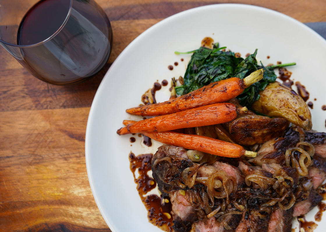 Sliced steak with glazed carrots, greens, and shallot sauce
